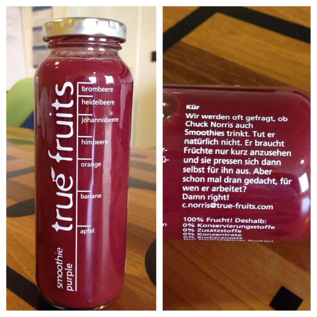 Left: A True Fruits smoothie bottle filled with a red liquid rests on a wooden table. Its front label features a list of ingredients in white text, including blackberry, blueberry, blackcurrant, raspberry, orange, banana, and apple. The iconic "true fruits" logo is printed vertically along the bottle. Right: The back of the bottle displays a witty message in white text about Chuck Norris. It claims that Chuck Norris doesn’t drink smoothies because fruits juice themselves when he looks at them. It then asks if the reader has ever wondered who Chuck works for, followed by the answer: “Damn right! c.norris@true-fruits.com”. Below the text, it proudly states: “100 % fruit! That’s why: 0 % preservatives.”